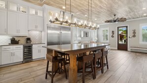 A modern kitchen with white cabinetry, stainless steel appliances, and a large island with bar stools.