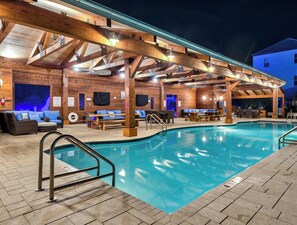 An indoor swimming pool with wooden beams and seating areas.