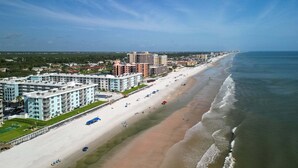 A coastal hotel with multiple buildings, a beach, and ocean views. - Top-floor 2/2 condo with ocean/pool views, private balcony, and heated beachfront pool (New Smyrna Beach)