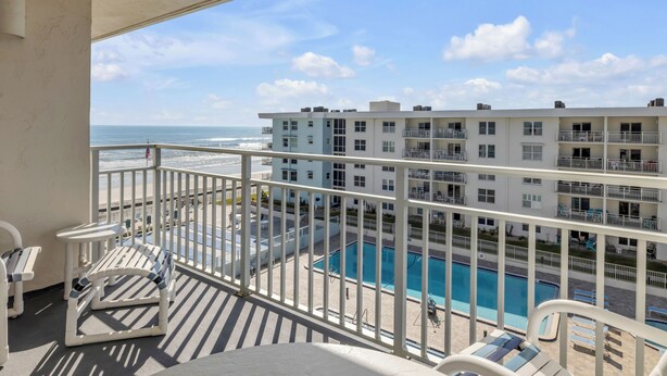 A balcony with a view of a swimming pool and ocean. - Top-floor 2/2 condo with ocean/pool views, private balcony, and heated beachfront pool (New Smyrna Beach)