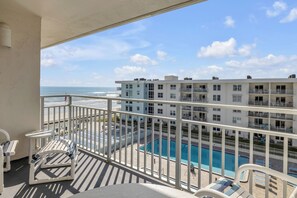Ein Balkon mit Blick auf einen Swimmingpool und das Meer.