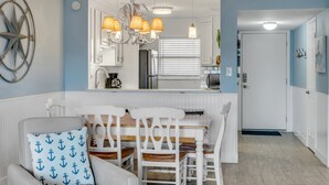 A dining area with a white table, chairs, and a chandelier. - Top-floor 2/2 condo with ocean/pool views, private balcony, and heated beachfront pool (New Smyrna Beach)