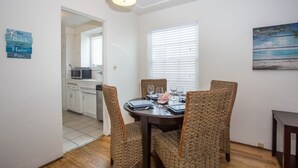 A dining area with a round table, wicker chairs, and a painting on the wall. - The Beach, Bay and Belmont Park right at your feet-Mission Beach (San Diego)