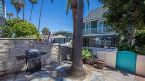 An outdoor patio with a stone floor, a grill, a palm tree, and a house in the background. - The Beach, Bay and Belmont Park right at your feet-Mission Beach (San Diego)