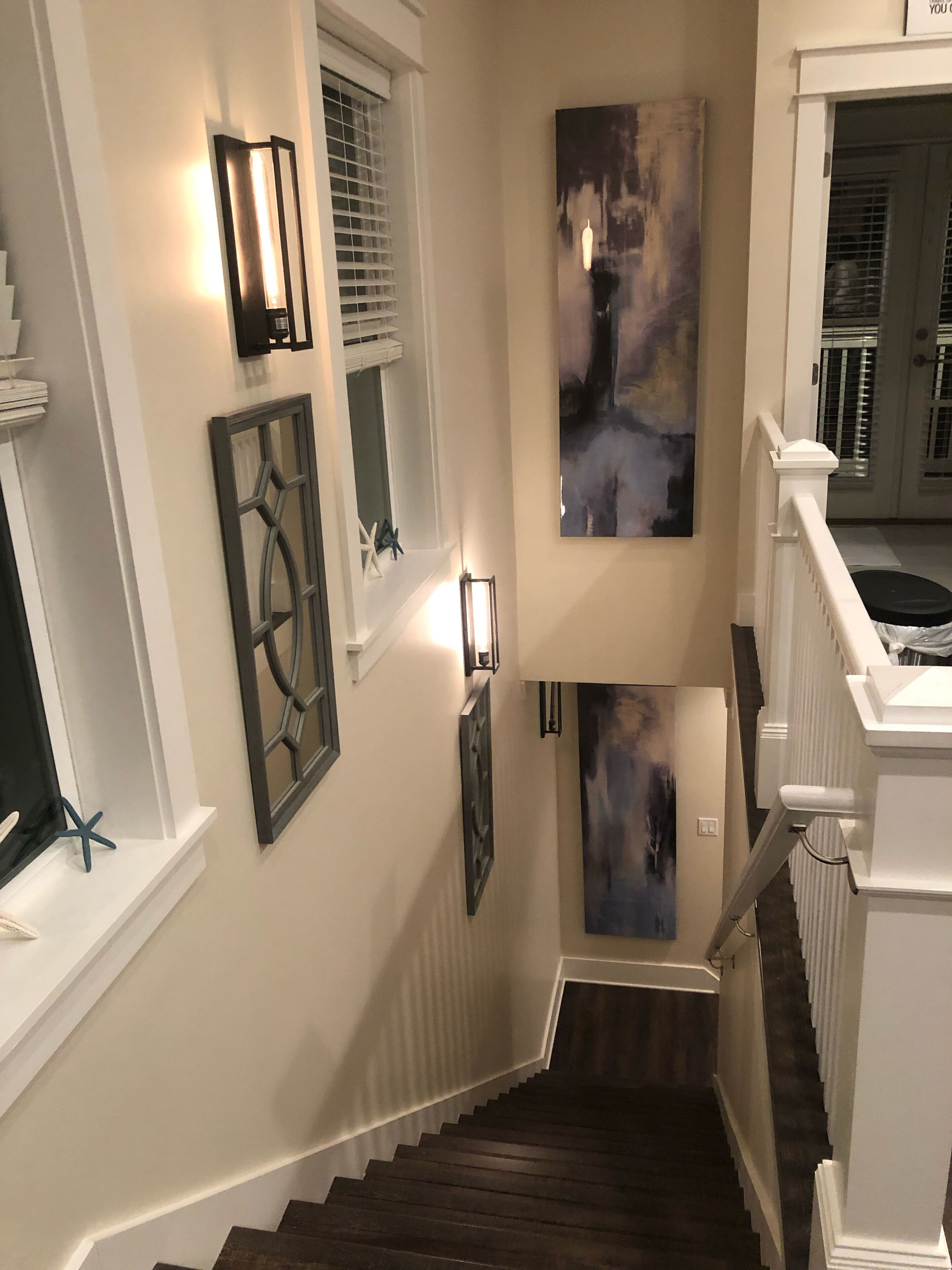 A staircase with dark wooden steps, white railings, and wall-mounted light fixtures.