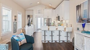 Una cocina moderna con armarios blancos, un refrigerador de acero inoxidable y una zona de bar con taburetes.