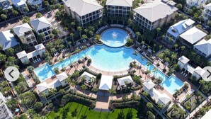 Vista aérea de un resort con varias piscinas, palmeras y una fuente central.