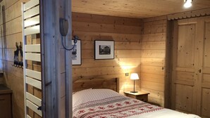 Una habitación de madera con una cama, una mesita de noche y una lámpara de pared.