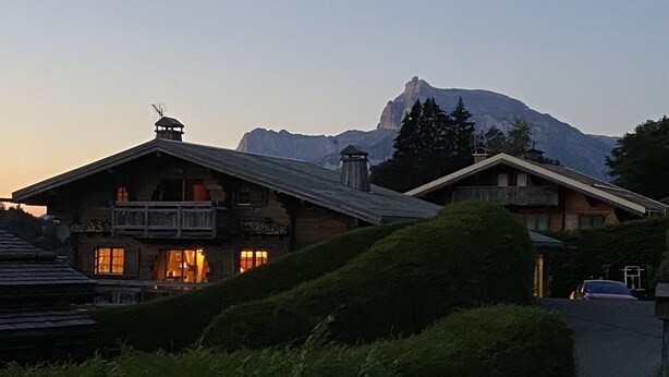 Un chalet tradicional con balcón, con montañas al fondo.