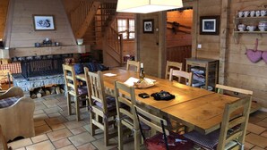 Un interior de madera con una mesa de comedor, sillas, una chimenea y una escalera.