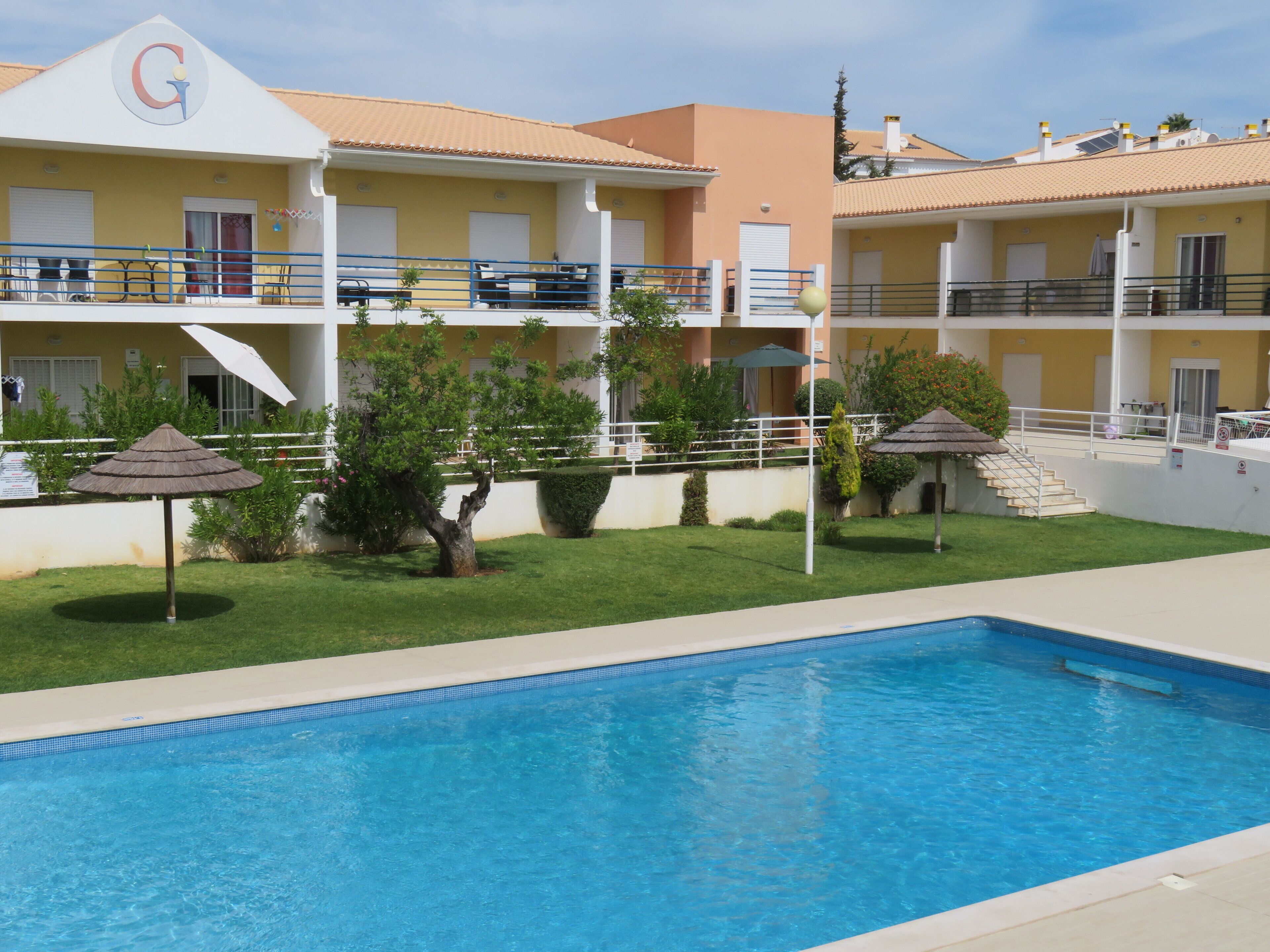 A hotel with a swimming pool, outdoor seating, and a well-maintained garden.