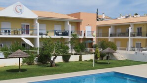 Un hotel con piscina, mobiliario exterior y un jardín bien cuidado.