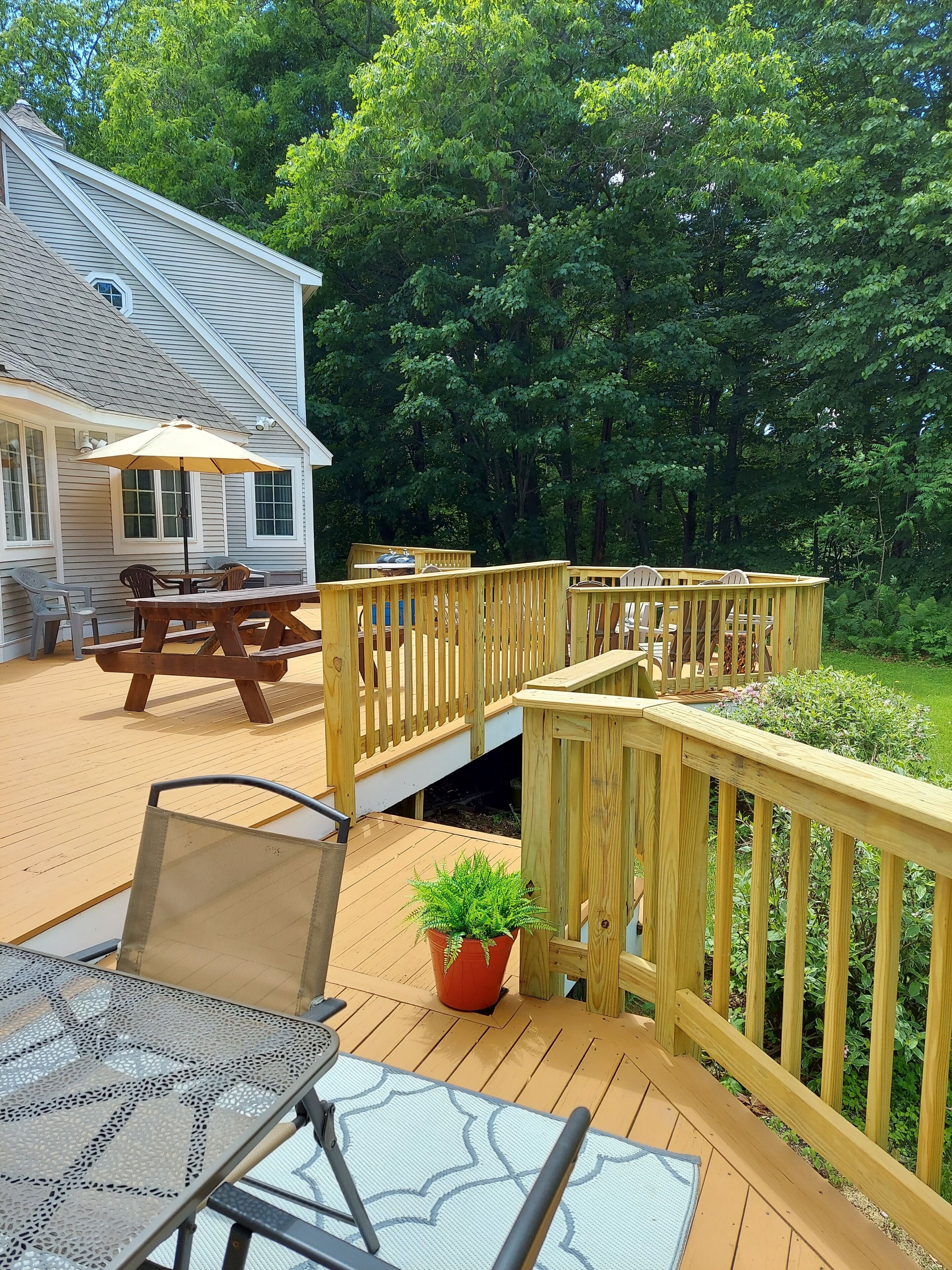 Une terrasse en bois avec une table et des chaises, un pot de fleurs et une maison en arrière-plan.
