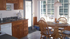 A kitchen with wooden cabinets, a dishwasher, and a dining area with a table and chairs. - Cool off in the Sunday River! Kayak to the Androscoggin. Spacious  Bethel home (Bethel)