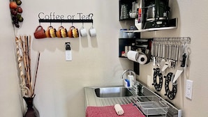 Eine kleine Küche mit Kaffeemaschine, Wasserkocher und verschiedenen Küchenutensilien.
