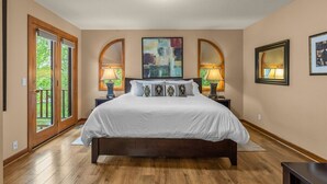 Una camera da letto con un letto grande, due lampade sui comodini, una luce a soffitto e vista panoramica attraverso una porta in vetro.