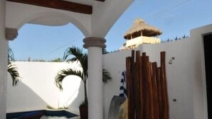 A covered outdoor area with a pool, columns, and a thatched-roof structure. - Spacious luxurious Apartment in Golden Zone (Bucerias)