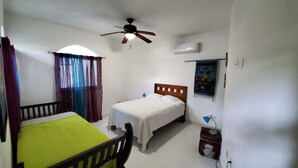 A bedroom with a single bed, a small table, a chair, a ceiling fan, and an air conditioning unit. - Spacious luxurious Apartment in Golden Zone (Bucerias)