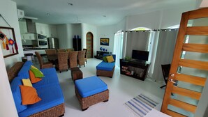 A living room with a sofa, ottoman, and chairs, a dining area with a table and chairs, a kitchen with appliances, and a TV on a stand. - Spacious luxurious Apartment in Golden Zone (Bucerias)