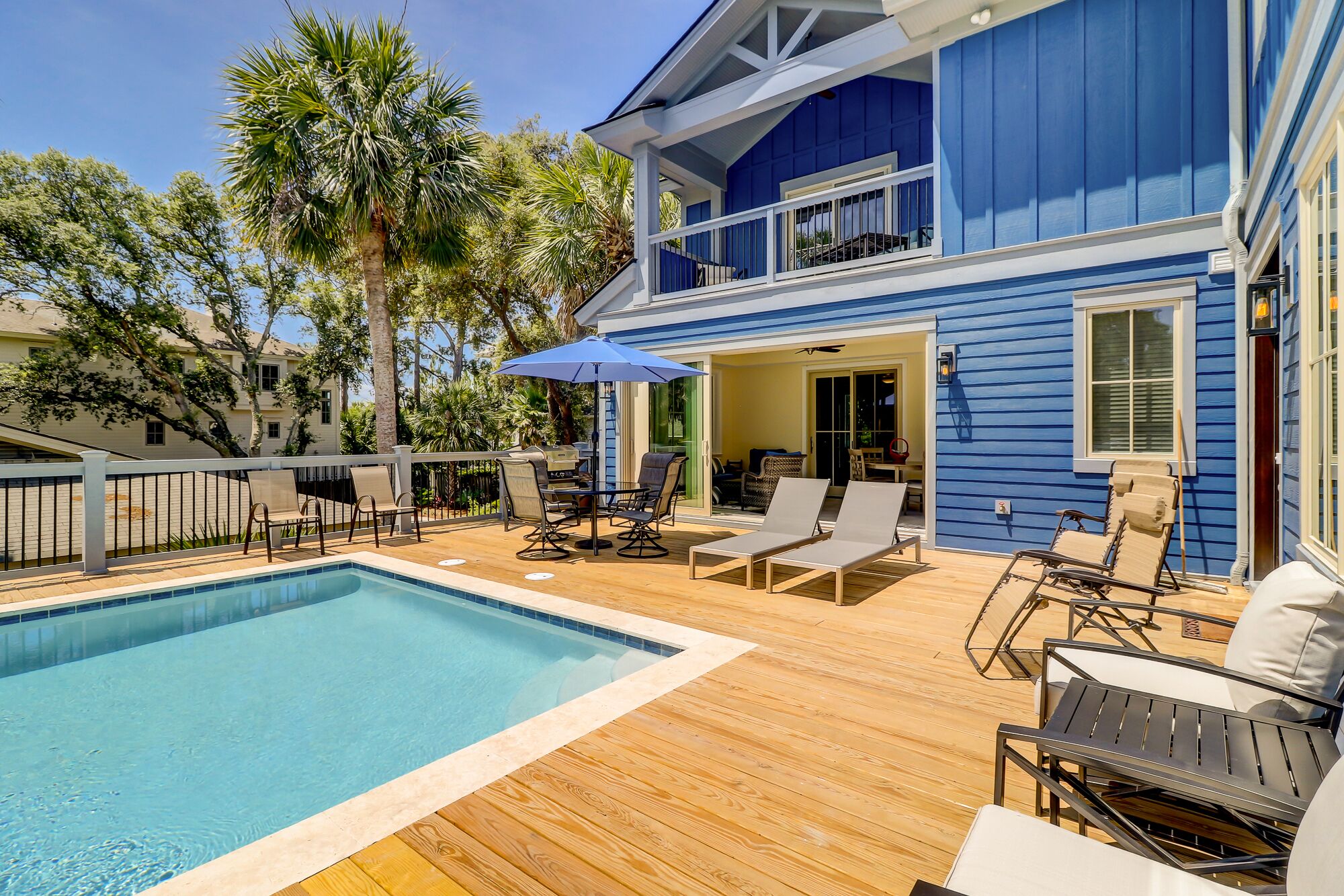 Un espace aménagé au bord de la piscine, avec une terrasse en bois, des chaises longues et un barbecue.