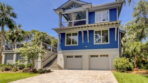 A two-story house with a blue exterior, a balcony on the upper floor, and a driveway leading to a garage. - 16 Bittern-3rd Row (85 yards) to the Ocean, Lowcountry home w/ private pool. (Hilton Head Island)