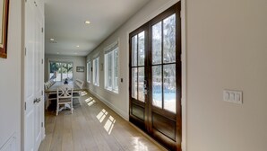 A hallway with a dining area, large windows, and a door with frosted glass. - 16 Bittern-3rd Row (85 yards) to the Ocean, Lowcountry home w/ private pool. (Hilton Head Island)