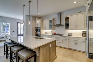 Una cocina moderna con una isla grande, electrodomésticos de acero inoxidable y armarios blancos.