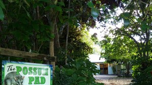 Señal de The Possum Pad, alojamiento vacacional con vistas a la propiedad y la vegetación circundante.
