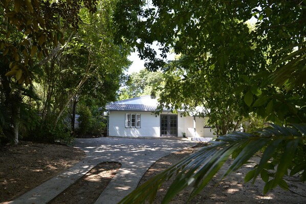 Una casa pequeña con techo inclinado, rodeada de abundante follaje.