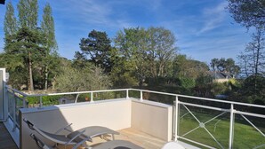 A balcony with two lounge chairs and a table, overlooking a well-maintained lawn and trees. - Arradon appart T3 Gulf of Morbihan, gite, southern Brittany valves (Arradon)