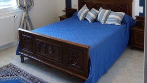 A bedroom with a wooden bed, a blue bedspread, and a patterned rug. - Arradon appart T3 Gulf of Morbihan, gite, southern Brittany valves (Arradon)