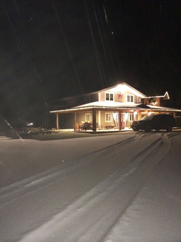 A two-story house with a snow-covered driveway and a car parked in front.