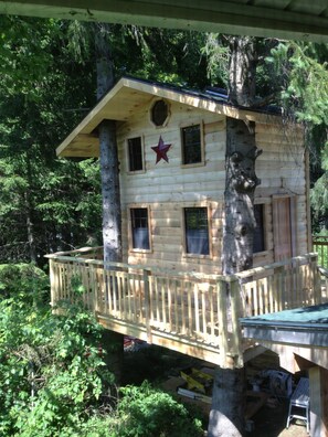 A wooden treehouse with a star decoration, multiple windows, and a balcony.