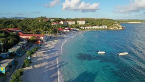Zona costera con playa, barcos y edificios de tejados rojos.