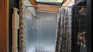A shower with a checkered floor, a patterned shower curtain, and a skylight above.