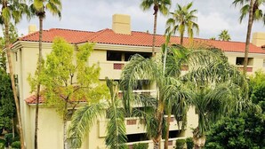 Un hotel con techo de tejas rojas, palmeras y un césped bien cuidado.