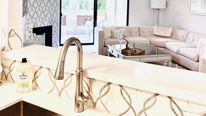 Una cocina moderna con un lavamanos de acero inoxidable, un ventilador de techo y un ventanal grande.