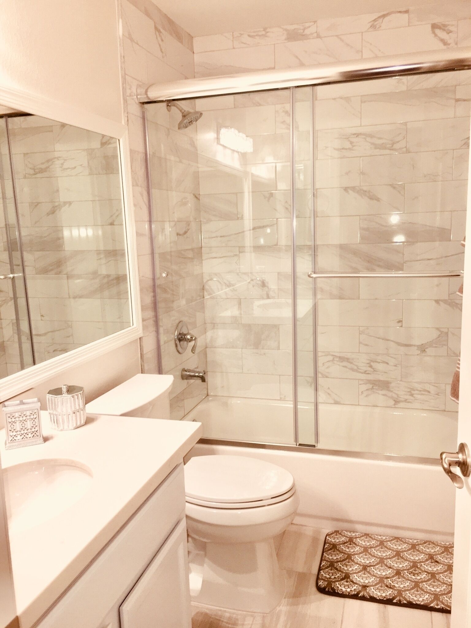 A bathroom with a glass-enclosed shower, a white toilet, and a vanity with a mirror.