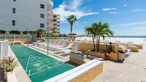 Ein Innenhof mit einem Shuffleboardfeld, Liegestühlen und einem Pool.