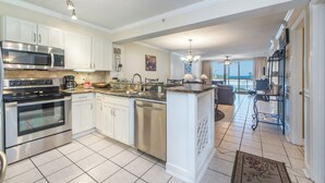 Una cocina moderna con electrodomésticos de acero inoxidable, una isla central y vistas a un balcón.