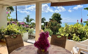 A covered patio with wicker furniture, a table with a compass design, and a view of the ocean.