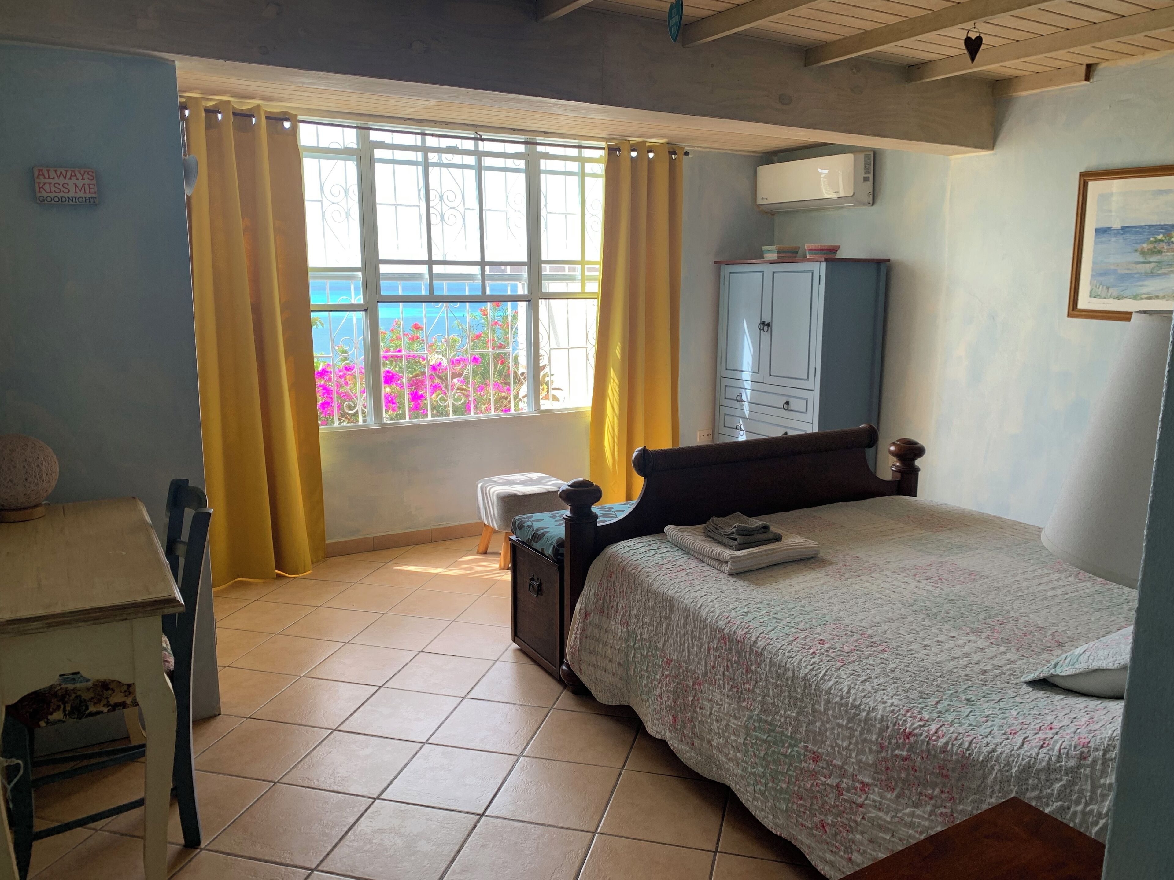 Une chambre à coucher avec un lit, un bureau, une armoire et une fenêtre avec des rideaux.