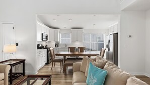 Una cocina moderna con armarios blancos, una mesa de comedor y un refrigerador.