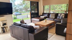 A modern living room with leather sofas, a coffee table, and a flat-screen TV. - Waterside, Pet Friendly Beach House (Vincentia)
