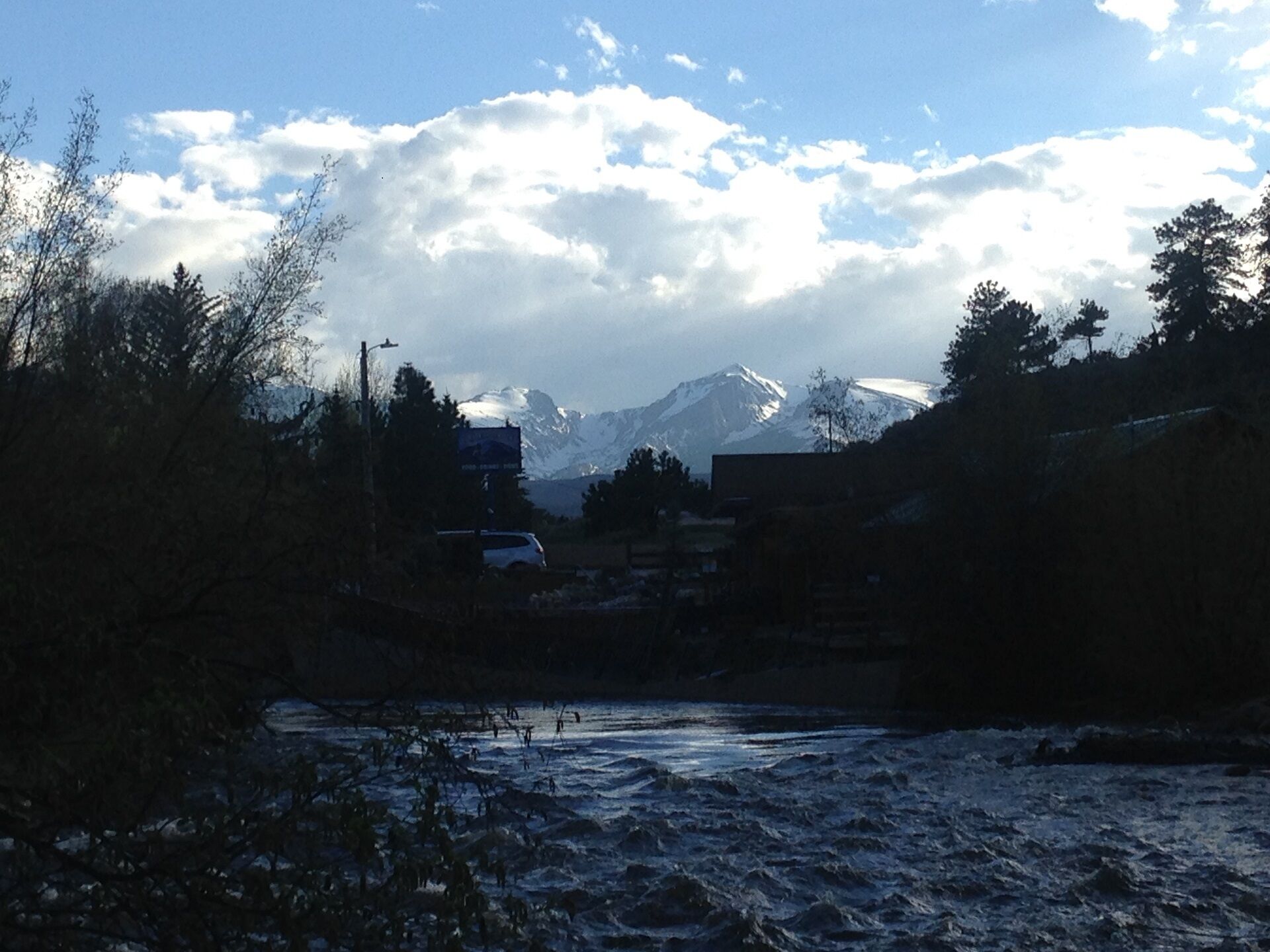 A river with a mountainous backdrop, surrounded by trees and buildings.