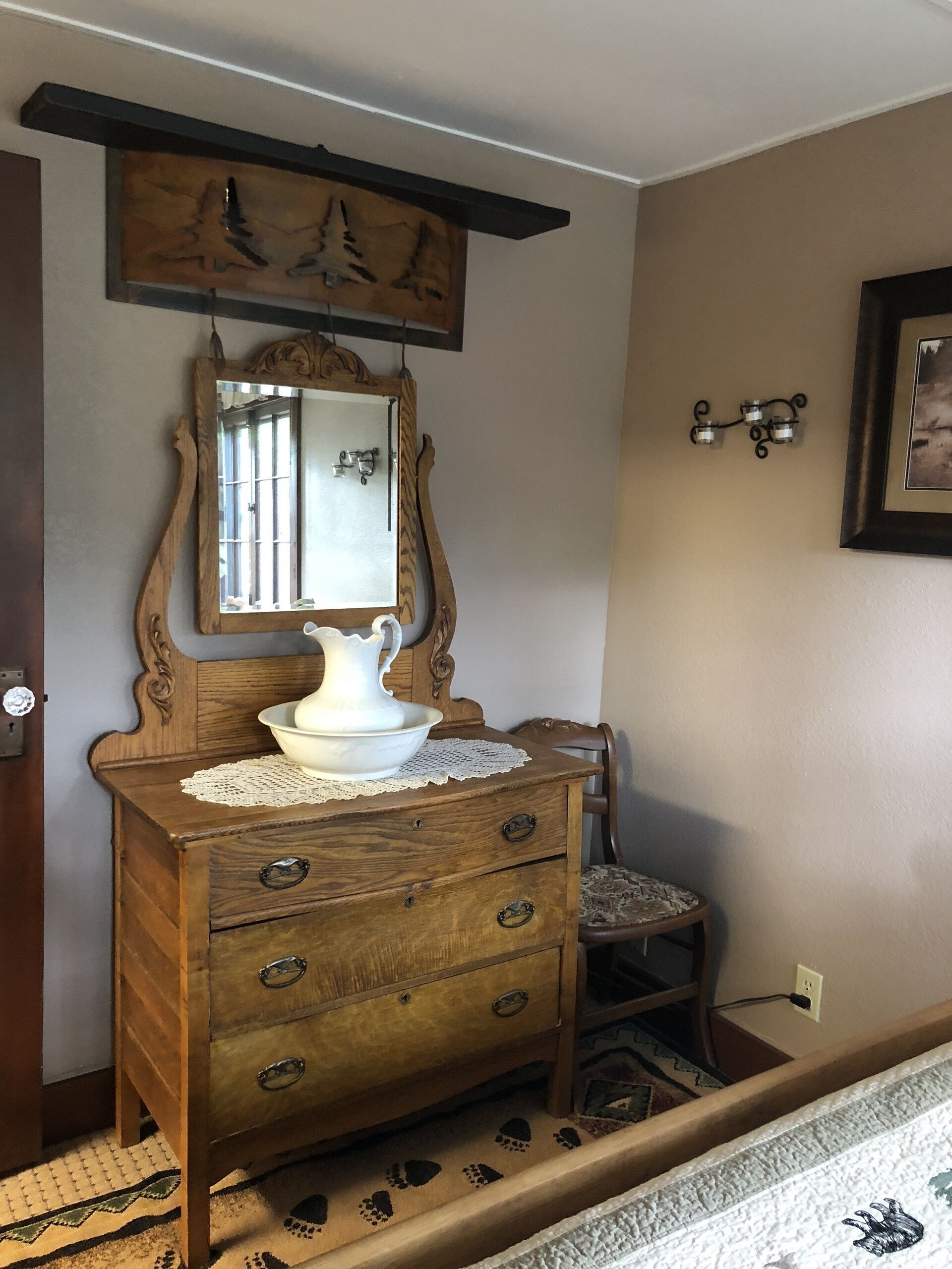 A wooden dresser with a mirror, a pitcher, and a lace doily.
