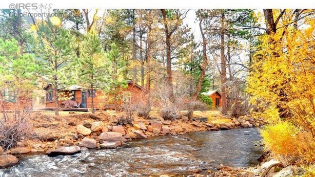 Une cabane au bord d’un ruisseau, entourée du feuillage automnal.