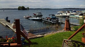 A marina with boats docked, a dock with a chair, and a grassy area with a flag.