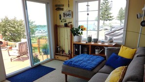 A cozy living room with a gray sofa, blue and yellow cushions, a blue blanket, and a fishing-themed wall decor.