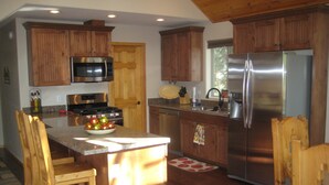 Una cocina con armarios de madera, electrodomésticos de acero inoxidable y una isla central con sillas.